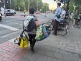 Eine Frau mit mehreren Taschen voller Pfandflaschen überquert eine Straße in der Nähe der Aaseewiesen.