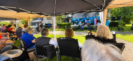 Bewohner, Gäste der Tagespflege und Besucher lauschen unter Pavillons dem Shanty-Chor.